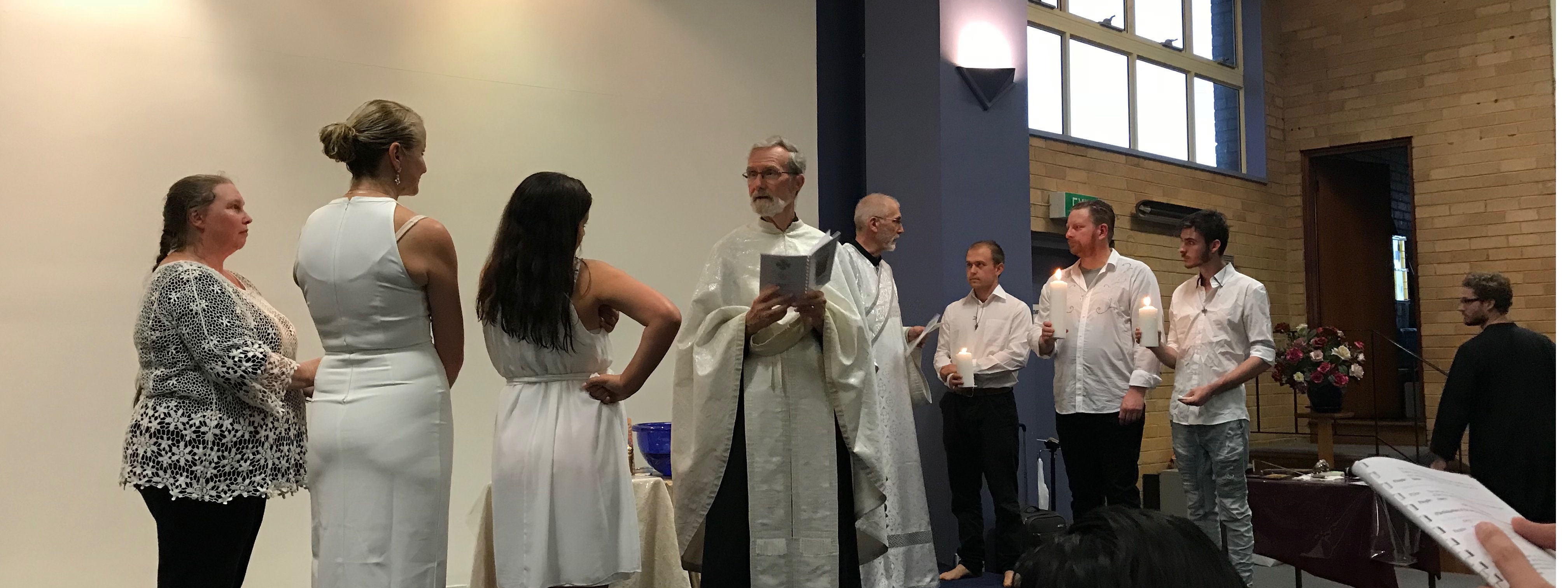 Fr. Geoff and Dcn. Nicholas and the baptismal candidates with lighted candles