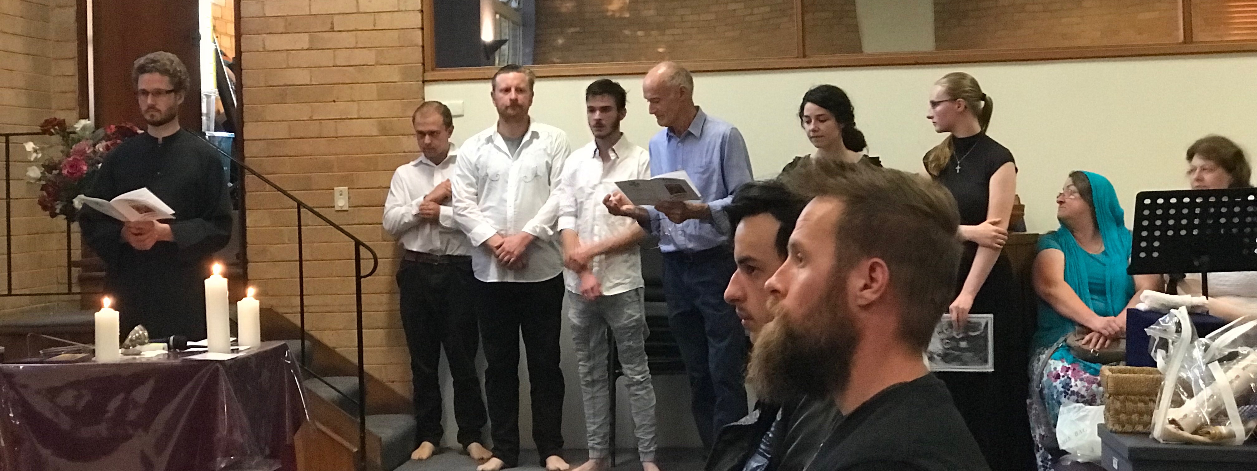 Two members of the congregation look on, with baptismal candidates and choir in the background